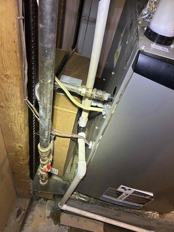 Responded to no-cooling complaint on aging air conditioning system paired with 2-year-old Bryant gas furnace in basement location. Customer reported unit unable to maintain temperature below 75 degrees during warm weather over the past several days. Performed diagnostic evaluation of complete HVAC system including inspection of indoor air handler, refrigerant lines, ductwork connections, and electrical components. Documented equipment conditions with photographic evidence showing existing installation configuration, PVC condensate drainage system, flexible duct connections, and overall mechanical room layout for service records.