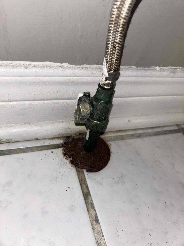 Responded to ongoing toilet leak in residential bathroom of 20+ year old home. Upon inspection, identified failed water supply line connection at fill valve with visible corrosion and seepage at floor-mounted shutoff valve. Replaced deteriorated braided supply line and corroded angle stop valve. Cleaned residual staining from tile flooring around connection point, tested system for proper operation and verified no additional leaks present.