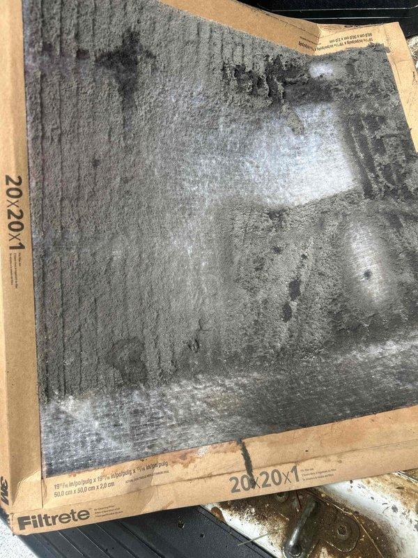 Responded to water leak complaint at indoor HVAC unit located in loft utility closet. Upon inspection, found severely clogged 20x20x1 air filter with heavy dust and debris accumulation restricting airflow. The restricted airflow caused evaporator coil to freeze, resulting in water dripping into bucket as ice melted. Replaced dirty filter with new unit, restored proper airflow to system, and verified no further water leakage occurring.