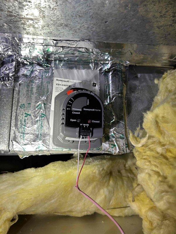 Completed Care Plan tune-up on a zoned air conditioning system with gas furnace located in basement. Inspected and serviced cylindrical air filter assembly, noting light dust accumulation on pleated filter media. Verified proper operation of Honeywell Home motorized damper control in ductwork, confirming dial indicators and electrical connections are functioning correctly. System operational with both zones responding appropriately to thermostat calls.