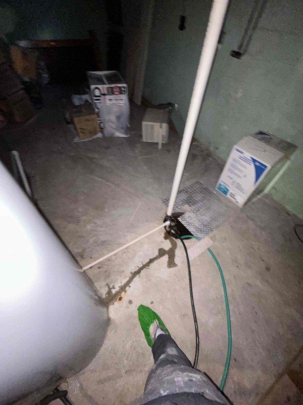 Responded to service call for 16-year-old tanked water heater with reported leaking underneath unit in basement location. Upon arrival, conducted visual inspection of water heater and surrounding area, documenting conditions with photographs. Assessed concrete floor for water damage and traced leak source to determine extent of issue and recommend appropriate repair or replacement options given age of equipment.