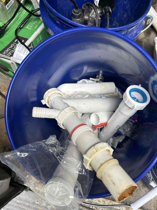 Responded to callback for leak under recently replaced kitchen sink. Upon inspection, identified active leak at drain assembly connection. Disassembled P-trap configuration and drain connections, finding improper seal at basket strainer. Reinstalled drain components with proper sealing, ensuring all PVC connections were secure and watertight. Tested system with running water to confirm leak was resolved. Photographed completed work showing proper P-trap installation and cabinet interior condition. Removed old fittings and materials from site.