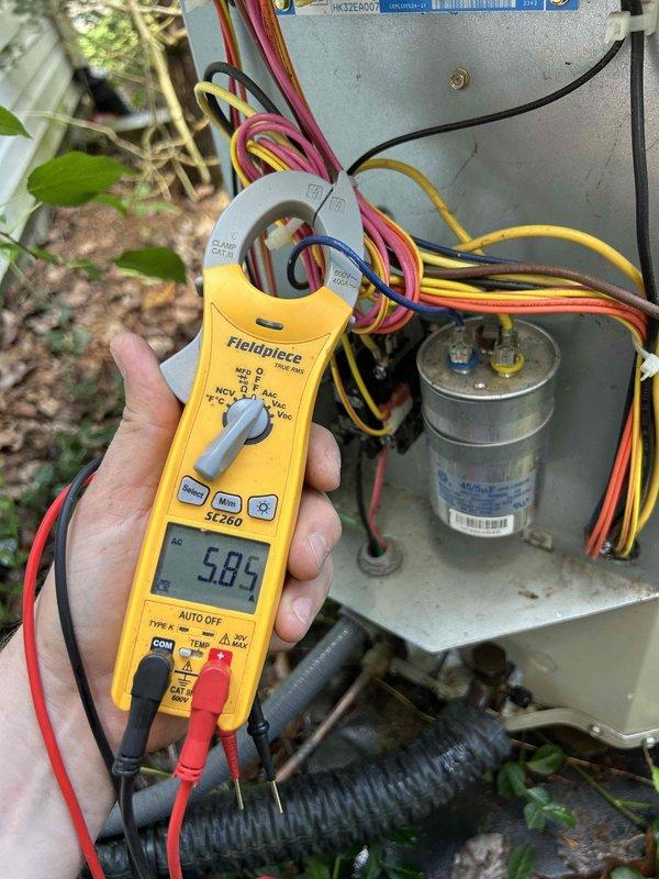Completed comprehensive care plan tune-up on heat pump system located in clean crawlspace. Performed electrical diagnostics using clamp meter to verify amperage readings on compressor circuit, measuring 5.85 amps with all wire connections tested at outdoor unit. Inspected capacitor, wiring connections, and internal components of condensing unit, confirming proper operation. Evaluated evaporator coil condition, noting dust and debris accumulation on aluminum fins requiring attention for optimal heat transfer efficiency.