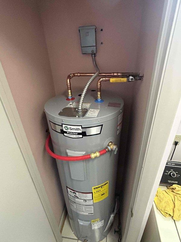 Responded to service call for no hot water condition on 8-year-old A.O. Smith ProLine tanked water heater located in residential utility closet. Upon arrival, performed comprehensive diagnostic evaluation of unit including inspection of gas supply line, pilot light assembly, thermocouple, gas control valve, and electrical connections. Verified proper gas flow through flexible metallic supply line and confirmed all plumbing connections at top of tank were secure with no visible leaks. Assessed copper piping configuration, brass fittings, and water line connections including the recirculation system components. Documented current condition of unit with detailed photographic records showing manufacturer labels, energy guide specifications, and overall installation setup. Unit appeared properly installed with adequate clearances and ventilation in confined space.