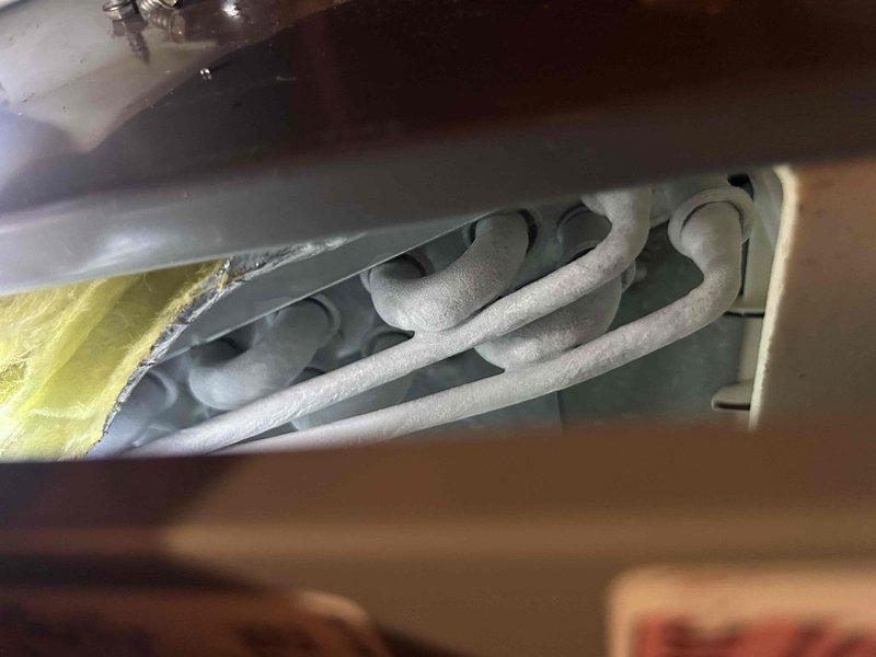 Responded to no cooling complaint on 6-year-old electric air conditioning system with indoor unit located in attic. Performed diagnostic inspection of evaporator coil assembly and refrigerant lines. Documented system components including serpentine coil configuration, refrigerant tubing, and insulation integrity. Verified recent filter change and assessed overall unit condition through visual inspection of internal components, fan housing, and mechanical compartment.