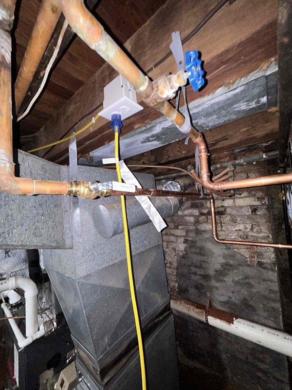 Completed tankless water heater installation in basement utility area requiring extensive infrastructure modifications. Drilled two exterior penetrations for fresh air intake and one for exhaust venting, then rerouted existing water supply and gas lines to accommodate new unit placement. Installed dedicated electrical outlet to power tankless system. Connected condensate drainage to existing sump pump alongside temperature and pressure relief valve discharge. Performed comprehensive leak testing on all water, gas, and condensate connections and verified proper operational functionality of the tankless water heater system before completing the installation.