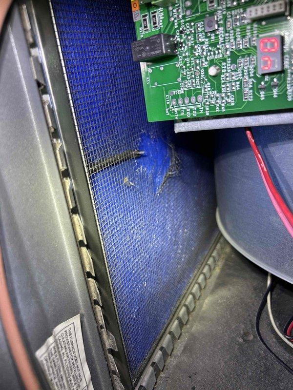 # HVAC Service Report

Responded to no-cool call for 15-year-old residential air conditioning system affecting entire home. Upon arrival, accessed attic-mounted air handler unit and performed diagnostic evaluation. Inspected internal components including control board with digital display and air filtration system. Noted blue mesh filter showing signs of debris accumulation and discoloration. Examined circuit board connections, wiring harness, and electrical components for proper operation. Documented equipment condition and internal components with photographs for service records.