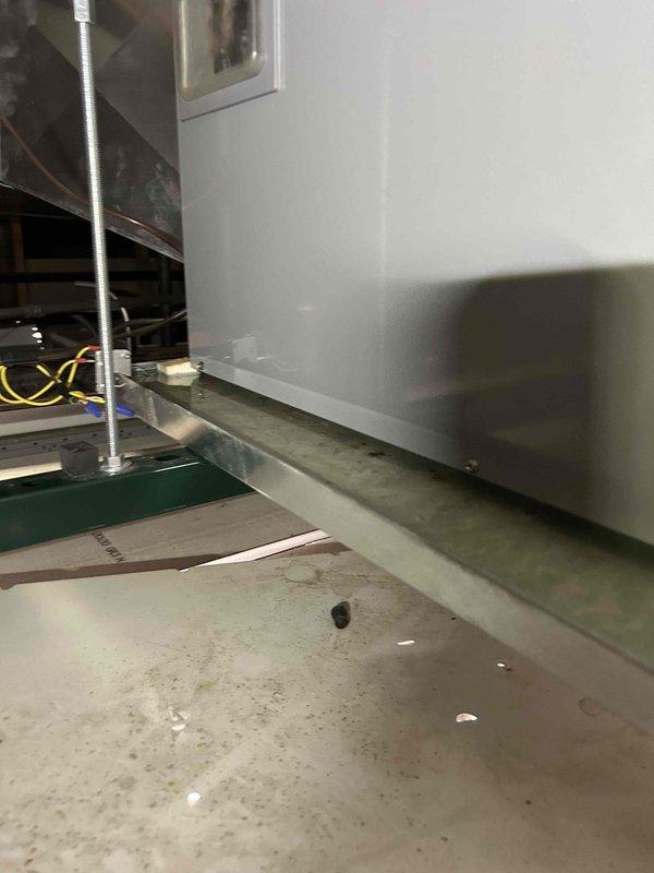Responded to commercial no cooling complaint and investigated reported water leak at overhead indoor unit located in center of building near supply room. Upon inspection of air handler, found evidence of moisture accumulation and drainage issues affecting system operation. Examined evaporator coil assembly, condensate drain system, and internal cabinet components. Identified blockage in condensate drain line causing water backup and steady dripping when unit operates. Cleared drain line obstruction, verified proper drainage flow, and tested system operation. Unit cooling properly with no further leakage observed.