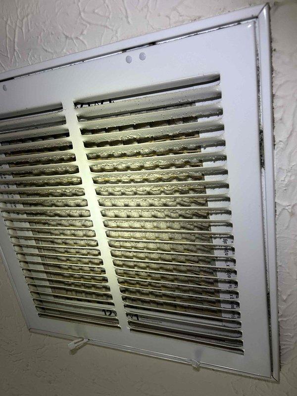 # HVAC Service Completed

Responded to a no cooling call on a 15-year-old air conditioning system. Upon arrival, performed diagnostic evaluation to identify the cause of cooling failure.

Initial inspection revealed severely restricted airflow due to heavy dust and debris accumulation throughout the return air system. Return grille showed significant buildup of airborne particles creating a matted layer on louvers and internal surfaces, indicating prolonged lack of maintenance. This restriction was substantially reducing system airflow and efficiency, contributing to the no cooling condition.

Proceeded to attic space to access air handling equipment and ductwork components. Evaluated air filter condition and accessibility. Due to deteriorated filter housing and compromised filter mounting system, fabricated custom filter rack assembly to ensure proper filtration and system protection going forward. Measured and cut materials on-site to create secure filter retention system that will m