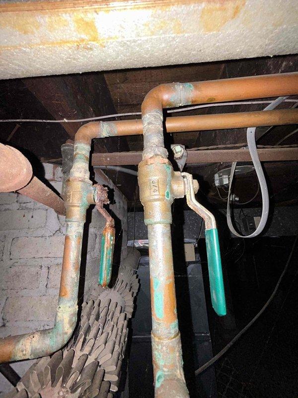 Responded to service call for older tanked water heater in basement with no hot water production. Upon inspection, found severely corroded and aged plumbing infrastructure with extensive oxidation on copper piping, shut-off valves, and connections throughout the system. Water heater tank displayed significant rust staining and deterioration consistent with age-related failure. Assessed circulator pump assembly, piping network, and heat exchanger components showing advanced wear and mineral deposit accumulation. Documented existing conditions including compromised valve operation due to corrosion buildup and overall system degradation requiring replacement recommendation.