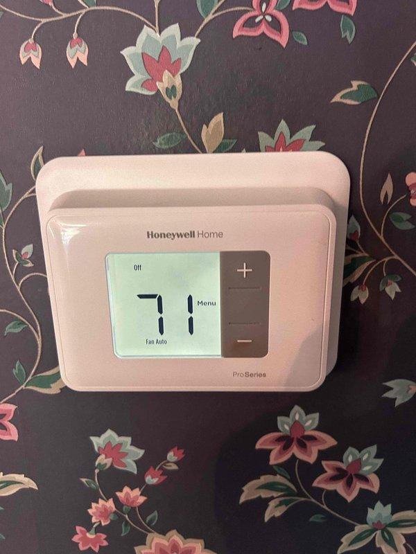 Responded to no cooling call on 11-year-old electric HVAC system affecting main floor unit. Upon arrival, found thermostat displaying 71°F while system was set to cool. Performed diagnostic testing of electrical components in outdoor condensing unit using digital multimeter. Measured voltage and amperage readings at capacitor and contactor assembly. Identified failed run capacitor reading 77.2 microfarads, significantly below manufacturer specifications. Replaced defective dual run capacitor with proper rated replacement. Cleaned electrical compartment of accumulated dust and debris. Verified proper voltage supply to compressor and condenser fan motor. Tested system operation through complete cooling cycle. Confirmed proper amperage draw on both compressor and fan motor. System restored to normal cooling operation with thermostat responding appropriately to temperature setpoint.