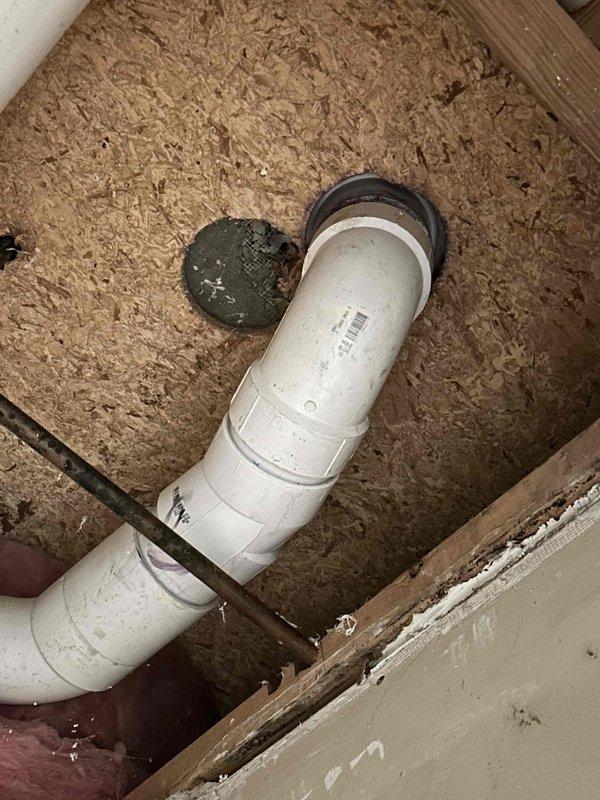 # Toilet Leak Repair and Cast Iron Waste Line Replacement

Responded to a chronic toilet leak in a 40-year-old residential property. Upon inspection, accessed the subfloor cavity beneath the affected bathroom to evaluate the plumbing waste system. Investigation revealed severely deteriorated cast iron waste piping serving the toilet fixture. The cast iron pipe exhibited extensive corrosion, material degradation, and structural compromise throughout multiple layers, with visible crumbling at connection points and significant buildup of corrosion byproducts.

Removed the failed section of cast iron waste line and replaced it with new white PVC drain pipe, utilizing black rubber couplings to ensure proper sealing at all connection joints. Installed appropriate fittings to maintain proper drainage slope and system integrity. Verified all connections were secure and leak-free. The replacement addressed the root cause of the ongoing leak issue, which had been caused by the deteriorated condi