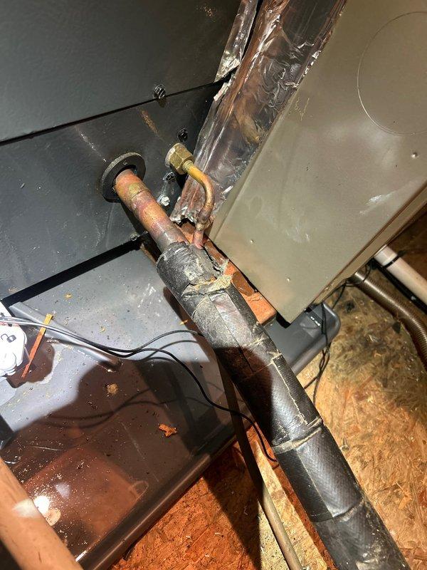 Responded to service call for water leak from attic-mounted indoor HVAC unit. Upon inspection, discovered minor water accumulation near the air handler, which had been temporarily contained with absorbent material. Performed thorough diagnostic examination of the condensate drain system, drain pan, and evaporator coil assembly. Inspected all copper refrigerant line connections and insulation for signs of condensation or moisture intrusion. Verified drain line was clear of obstructions and flowing properly. Examined flexible ductwork connections and plenum assembly for any signs of moisture damage or air leakage that could contribute to condensation issues. Documented system conditions with photographic evidence showing plumbing connections, insulation integrity, and attic installation configuration for reference.