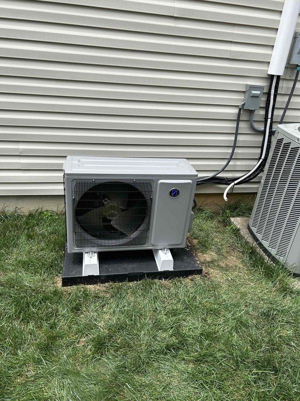 Completed installation of Friedrich 12,000 BTU ductless mini-split system (model FPHSR12A3D outdoor unit, FAHFW12A3D indoor wall-mount unit) at residential property. Positioned outdoor condenser on ground-level composite pad with mounting feet adjacent to existing HVAC equipment per homeowner request, avoiding wall-mounted installation. Installed dedicated 220V 20-amp electrical circuit with disconnect box, electrical whip kit, and proper conduit routing along exterior siding. Ran refrigerant lines with insulation between outdoor and indoor units, completed vacuum and pressure testing, and charged system to manufacturer specifications. Mounted indoor wall unit, established electrical and refrigerant connections, and verified proper operation of heating and cooling functions. Installation includes applicable permits and meets code compliance requirements, with 1-year labor warranty and 10-year parts warranty coverage.