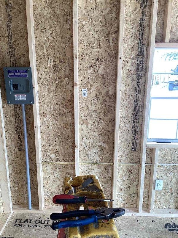 Completed electrical rough-in for pavilion structure, installing 100-amp service panel with two breakers, GFCI receptacle, two duplex outlets, single-pole switch, and two keyless fixtures with bulbs. Ran conduit from main panel through exposed wall framing and coordinated wiring installation with ongoing construction phase. All electrical components installed per code requirements in preparation for final inspection and drywall installation.