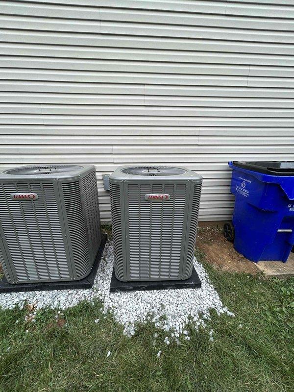 Completed residential HVAC installation of two Lennox ML14KC1-024-230 2-ton air conditioning units rated at 14.7 SEER2 with matching CK40CT-18/24B-71 evaporator coils. Both condensing units were installed on mounting pads over white gravel base against exterior wall with proper clearances maintained. Integrated existing thermostats with new systems, obtained applicable permits, and removed and disposed of existing equipment. Both outdoor units were positioned side by side on the building's exterior, professionally leveled and secured on black composite pads with adequate spacing for service access and airflow. All refrigerant lines were properly sized and insulated, electrical connections completed to code specifications, and condensate drainage systems installed and tested. Systems were charged to manufacturer specifications, leak tested, and verified for proper operation including temperature differential, airflow, and refrigerant pressures. Final installation included enrollment in 