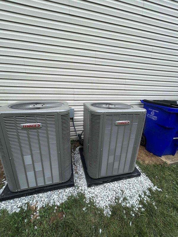 Completed residential HVAC installation of two Lennox ML14KC1-024-230 2-ton air conditioning units rated at 14.7 SEER2 with matching CK40CT-18/24B-71 evaporator coils. Both condensing units were installed on mounting pads over white gravel base against exterior wall with proper clearances maintained. Integrated existing thermostats with new systems, obtained applicable permits, and removed and disposed of existing equipment. Both outdoor units were positioned side by side on the building's exterior, professionally leveled and secured on black composite pads with adequate spacing for service access and airflow. All refrigerant lines were properly sized and insulated, electrical connections completed to code specifications, and condensate drainage systems installed and tested. Systems were charged to manufacturer specifications, leak tested, and verified for proper operation including temperature differential, airflow, and refrigerant pressures. Final installation included enrollment in 