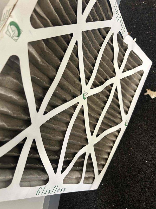 Responded to no cooling complaint at commercial office location. Upon arrival, found indoor air handler had frozen evaporator coil which resulted in water damage to drop ceiling tiles below unit. Inspected system and discovered heavily soiled air filters restricting airflow, which was primary cause of freeze-up condition. Removed and replaced dirty filters with new Glasfloss filters to restore proper airflow. Examined electrical components and noted significant corrosion on metal surfaces and terminal connections, indicating previous moisture exposure from condensate issues. Allowed coil to fully defrost before system restart. Tested system operation after defrost cycle completed and verified adequate airflow and cooling performance restored. Advised that corroded electrical components and connections should be monitored closely and may require future replacement to prevent potential failures. System operational at time of departure with proper cooling restored.