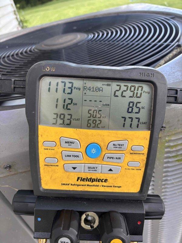 Completed preventive maintenance tune-up on heat pump system with air handler located in attic accessible via pull-down stairs. Performed comprehensive system diagnostics on outdoor unit using refrigerant manifold gauge, confirming R410A refrigerant charge with pressures reading 117.3 psig low side and 229.0 psig high side, with superheat and subcooling measurements recorded. Verified thermostat operation and programming on Honeywell ProSeries digital control set to 67 degrees.