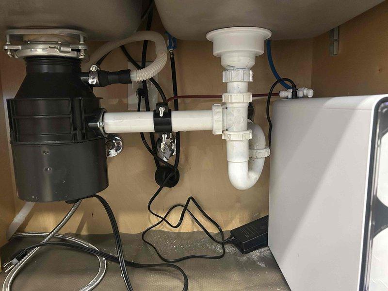 Supplied and installed a new Aqua Flo tankless reverse osmosis drinking water system beneath the kitchen sink. The installation included mounting the RO unit in the cabinet, connecting it to the existing cold water supply line, routing purified water to a dedicated gooseneck faucet installed on the countertop, and establishing proper drain connections to the existing P-trap assembly. All plumbing connections were secured and tested for leaks, with the system positioned to allow adequate clearance around the existing garbage disposal unit and drainage configuration.