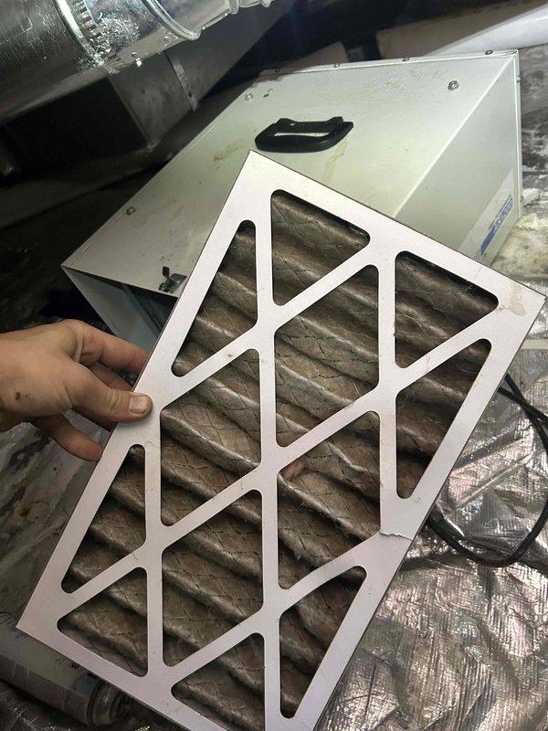 Responded to customer complaint of foul odor emanating from ductwork and permeating throughout the residence. Performed comprehensive inspection of HVAC system including crawlspace access to examine ductwork integrity and identify odor source. Located heavily soiled air filter with significant dust and debris accumulation, which was contributing to poor air quality and musty smell circulation. Inspected exposed ductwork, copper refrigerant lines with insulation, PVC condensate drainage, and flexible ducting in crawlspace area for signs of moisture intrusion, biological growth, or structural damage that could cause odors. Documented condition of filter media showing dark brown discoloration and verified filter housing unit accessibility. Examined crawlspace environment including gravel vapor barrier coverage and building infrastructure for potential moisture issues or organic material decomposition that could generate crawlspace odors being drawn into the air distribution system.