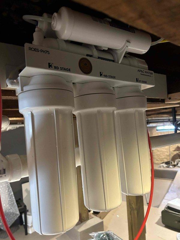 Completed filter cartridge replacement on APEC ROES-PH75 reverse osmosis water treatment system. Removed and replaced three-stage pre-filtration cartridges including sediment and carbon block filters, restoring system to optimal operating condition.