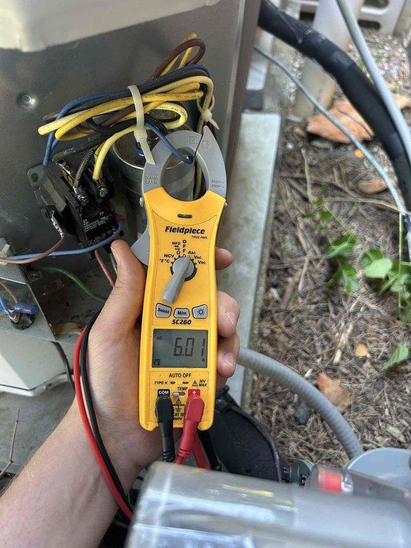 Responded to no cooling complaint on 4-year-old gas furnace/air conditioning system. Upon arrival, customer reported raccoon damage to ductwork in attic. Performed complete system inspection including electrical diagnostics at outdoor condensing unit using clamp meter to verify proper amperage draw and component operation. Accessed attic-mounted air handler and inspected flexible ductwork system. Found damaged duct insulation and compromised duct integrity from animal intrusion as reported. Documented existing conditions with photos showing worn reflective insulation wrap with tears exposing underlying duct material, and measured temperature differentials across affected ductwork sections. Verified outdoor unit electrical components functioning within normal parameters with 6.0 amp reading observed during testing. System operational but requires ductwork repair to restore proper airflow and efficiency.