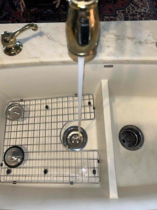 Responded to leak under kitchen sink in 38-year-old home. Upon inspection, identified cracked PVC drain pipe beneath the double-basin kitchen sink as the source of the leak that had been active for 2-3 days. Replaced the damaged PVC drain section and installed two new chrome escutcheon plates (decorative covers) at the supply line connections to restore proper appearance and function. Verified all connections were secure with no active leaks, tested water flow through both basins, and confirmed proper drainage operation before completing the service call.