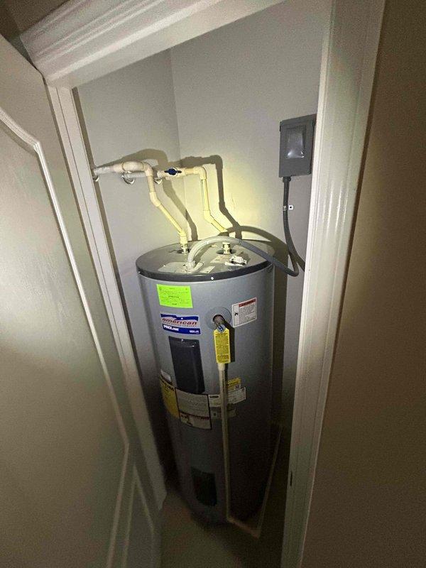 Performed routine plumbing inspection of residential water heater system. Inspected American brand water heater unit, verified proper installation of inlet/outlet connections, PVC piping, pressure relief valve, and electrical components. All components found in good working condition with no visible leaks, corrosion, or safety concerns identified.