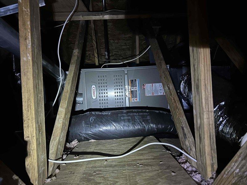 Completed annual care plan maintenance on air conditioning system with gas furnace located in attic space. Performed comprehensive tune-up inspection of indoor air handler unit, checking all operational components, electrical connections, and airflow systems. Verified proper operation of blower motor and examined ductwork connections for secure mounting and adequate insulation. Inspected outdoor Lennox condenser unit, noting significant fire or heat damage to surrounding area including charred material on adjacent trash receptacle and thermal damage to vinyl siding near electrical connection point. Documented damaged and displaced paver stones around equipment pad. Despite external environmental damage, confirmed AC unit operational functionality and proper refrigerant levels. Customer provided air filters as specified in service agreement, which were installed per manufacturer specifications.