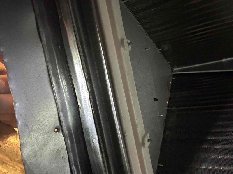 Responded to no cooling complaint on 5-year-old Trane air conditioning unit located in upstairs bathroom mechanical closet. Upon arrival, performed diagnostic inspection of system including air handler, ductwork, and condensate drain lines. Inspected vertical HVAC equipment installation, examined heat exchanger coil assembly, and verified proper mounting and connections of all components. Documented system configuration with metallic insulated ductwork, black PVC condensate piping with multiple couplings, and electrical conduit routing. System evaluated and customer advised of findings.