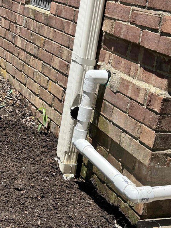 Returned to property to correct condensate discharge line routing to gutter as previously requested. Repositioned white PVC drainage piping along exterior brick wall, installing proper elbow fittings and horizontal run to direct discharge away from foundation and toward gutter system. Secured all piping with appropriate mounting brackets to ensure proper support and alignment, preventing future sagging or separation of joints.