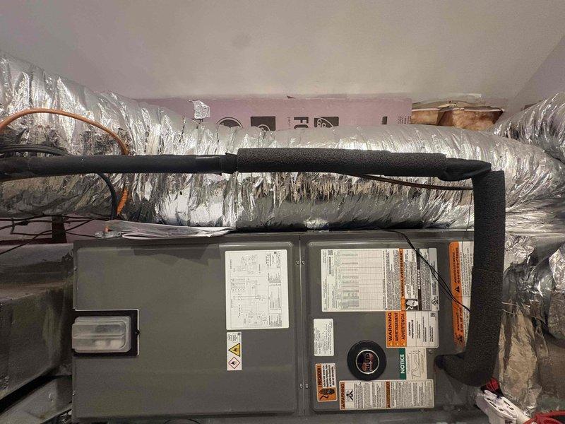 Completed full HVAC system replacement in attic space, installing RUUD/Rheem 3-ton two-stage heat pump (model RP14AY36AJ2NA, 15.2 SEER2) as outdoor unit, RUUD/Rheem 3-ton air handler (model RH2TY3617STANNJ), and 15 KW heat kit (model RXBH-1724A15J-B). Removed and disposed of existing equipment per code requirements. Installed outdoor unit on new pad with snow legs, electrical disconnect box, and whip kit. Connected refrigerant lines between outdoor unit and air handler. Mounted air handler in attic space and integrated 15 KW supplemental heat kit for backup heating. Installed approximately 8 feet of duct board at damper locations to facilitate proper airflow distribution. Connected new system to existing zone control system and thermostats, maintaining multi-zone functionality throughout residence. Installed drain trap, SS2 coil drain safety water sensor, and "Ceiling Saver" overflow drain pan with water sensor for secondary condensate protection. Fabricated transitions to connect new 