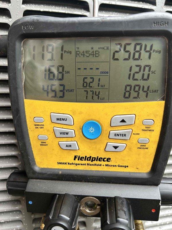 Responded to install callback for reported line set leak with white film present on refrigerant lines. Upon arrival, inspected exterior line set connections and observed moisture accumulation and surface condensation on copper lines and mounting bracket assembly. Connected Fieldpiece SMAN manifold gauge set to system and recorded operating pressures of 119.1 psig low side and 258.4 psig high side with R454B refrigerant, superheat at 16.9°F and subcooling at 120°F. System operating within normal parameters with no immediate refrigerant loss detected. Photographically documented line set condition and gauge readings for follow-up assessment. White film determined to be condensation-related surface deposits rather than refrigerant leak. Recommended continued monitoring and scheduled follow-up inspection to verify system integrity.
