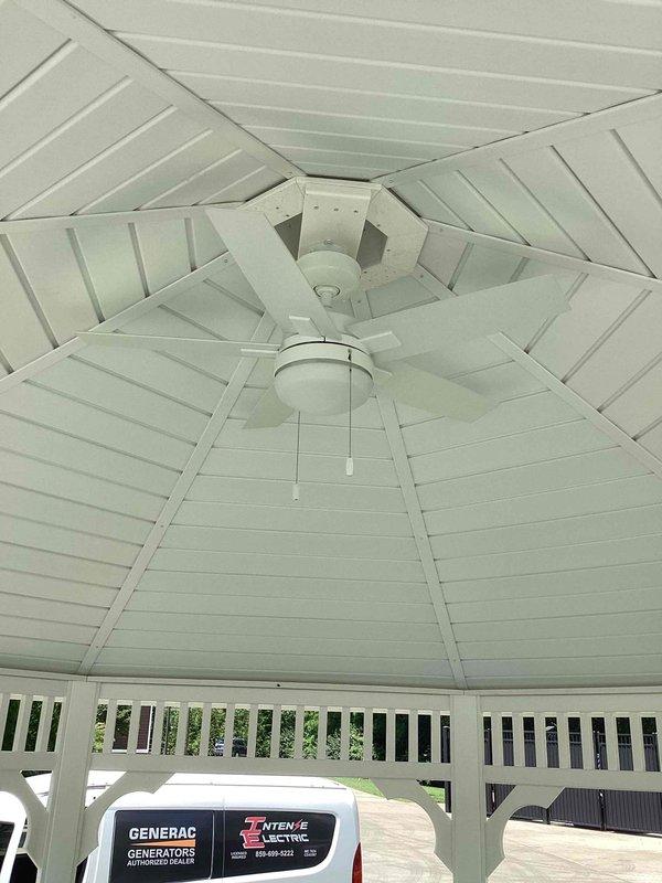 Successfully installed white outdoor-rated ceiling fan with integrated light kit in gazebo structure. Completed all electrical connections, mounted unit to central hub of octagonal ceiling, and verified proper operation of both fan motor and lighting fixture with pull chain controls.