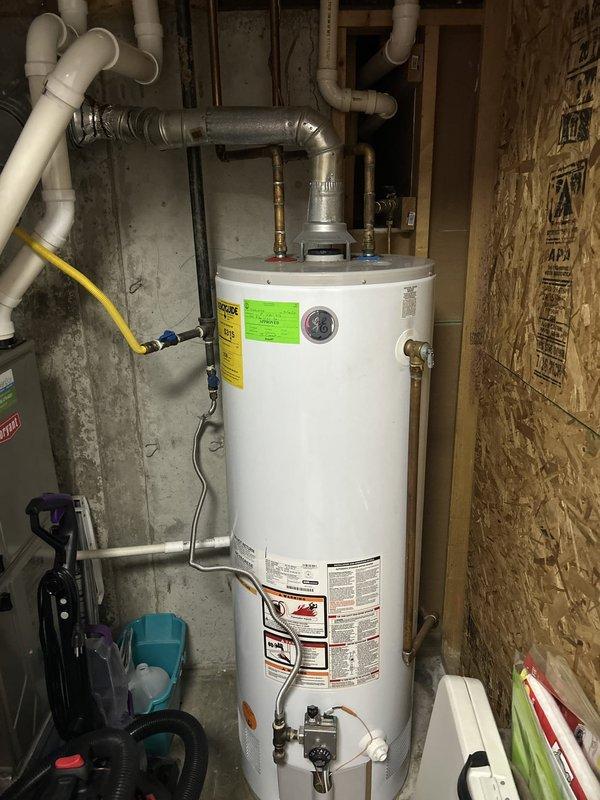 Completed routine plumbing maintenance inspection of residential property. Inspected water heater installation in basement utility area, verifying proper connections of water supply lines, gas line, and PVC vent piping; confirmed temperature and pressure relief valve accessibility and noted all safety labels present. Examined under-sink plumbing fixtures including P-trap configuration and drain connections, finding all components properly installed with no visible leaks or deficiencies at time of inspection.