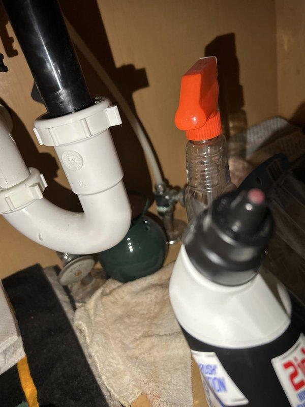 Completed routine plumbing maintenance inspection of residential property. Inspected water heater installation in basement utility area, verifying proper connections of water supply lines, gas line, and PVC vent piping; confirmed temperature and pressure relief valve accessibility and noted all safety labels present. Examined under-sink plumbing fixtures including P-trap configuration and drain connections, finding all components properly installed with no visible leaks or deficiencies at time of inspection.