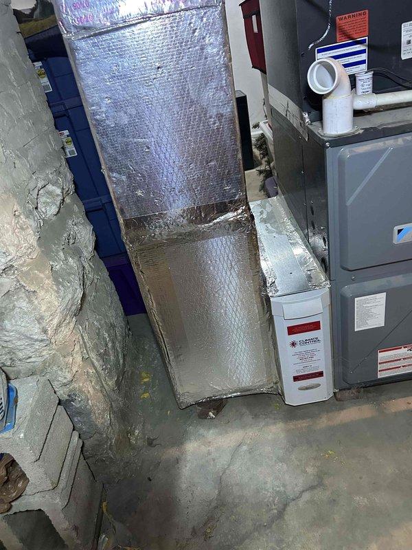 Replaced damaged ductwork section in basement mechanical room using two sheets of ductboard to fabricate a 12x22 inch rectangular duct with end cap. The new duct section was installed to replace deteriorated ductwork that showed significant dust accumulation, staining, and wear, restoring proper airflow and system efficiency.