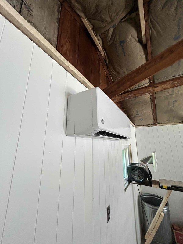 Completed installation of customer-provided mini-split system in detached garage, mounting both indoor and outdoor units. The indoor air handler was wall-mounted on finished beadboard paneling in the upper level space with exposed structural framing. All refrigerant lines, electrical connections, and condensate drainage were properly installed and tested for functionality, with the system confirmed operational upon completion.