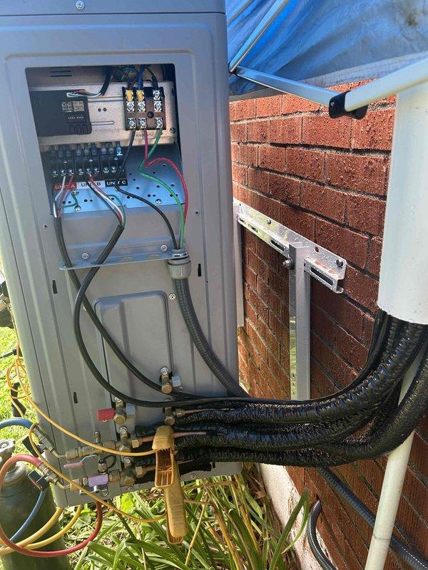 Completed full installation of a Friedrich 2-ton dual-head mini-split system. Mounted two indoor air handler units in upper-level rooms with sloped ceilings, positioning units on interior walls with proper clearances for optimal airflow distribution. Installed outdoor condensing unit on exterior brick wall using heavy-duty wall mounting bracket to ensure secure attachment and proper elevation above grade.

Ran new communication line set and refrigerant lines from both indoor heads through wall penetrations to outdoor unit location, ensuring proper insulation and protection of all refrigerant piping. Installed new electrical wiring from indoor units to outdoor condensing unit, routing conductors through liquid-tight flexible conduit for weather protection. Made all electrical terminations at outdoor disconnect box, connecting line voltage conductors to terminal blocks with proper torque specifications. Verified all wire connections were secure and met code requirements.

Performed vacuu