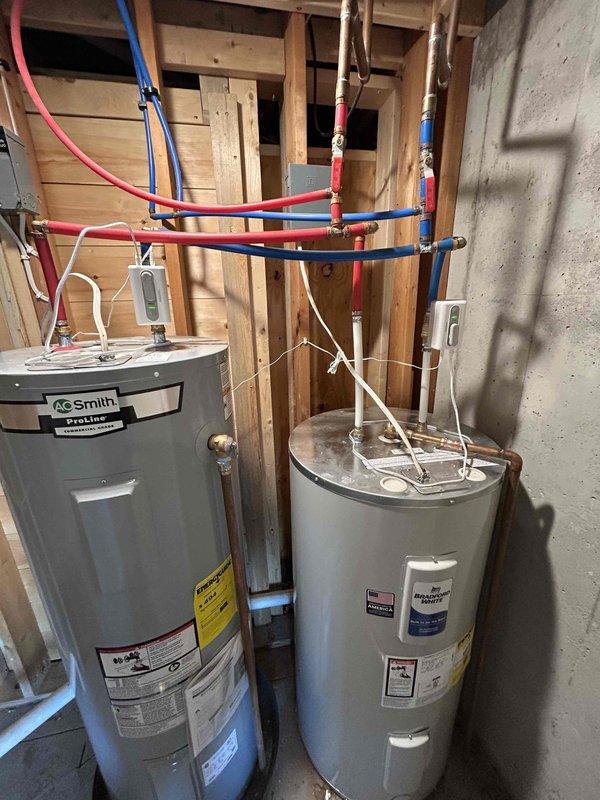 Installed dedicated 120V duplex receptacle outlet in unfinished utility area to provide power for dual water shut-off valves servicing two water heaters. Mounted outlet box on exposed wall framing and ran electrical cable from power source to new outlet location. Completed installation per specifications with all wiring properly secured to structural members.