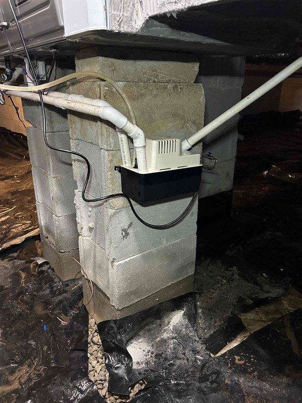 Returned to property to address crawl space flooding issues and equipment relocation. Replaced shorted condensate pump that had failed due to water exposure and mounted new unit on cinder block support column to elevate above ground level. Relocated AprilAire dehumidifier from garage back to crawl space and secured unit to floor joists using metal straps per customer preference, eliminating ground contact and reducing future flood risk. Verified proper drainage connections and electrical operation of both units before completing installation.