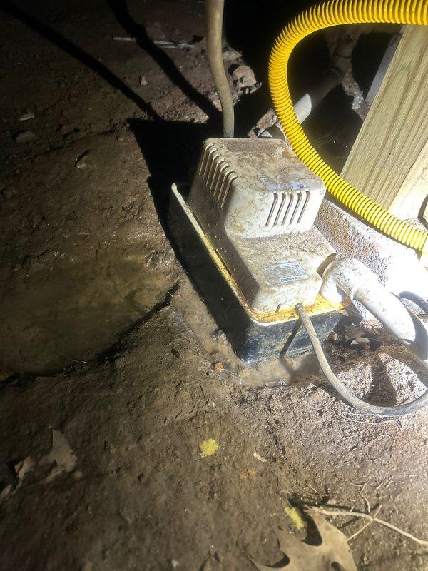 Responded to no cooling complaint on 10+ year old electric AC system with front of house unable to reach setpoint of 72°F, climbing to 79°F. Upon inspection of crawl space where indoor unit is located, found extensive deterioration of flexible ductwork insulation with multiple tears and exposed sections throughout the supply duct runs. Insulation vapor barrier had separated and was hanging loose in several areas, compromising thermal efficiency and allowing significant temperature gain in conditioned air before reaching living spaces. Observed wooden support framing beneath damaged ductwork and noted accumulated debris on crawl space floor surfaces. Located condensate removal equipment covered in heavy dust accumulation, indicating extended period without maintenance. Yellow flexible condensate line routing from pump assembly appeared functional but entire area showed signs of neglect. Documented compromised ductwork condition and explained how deteriorated insulation and potential air