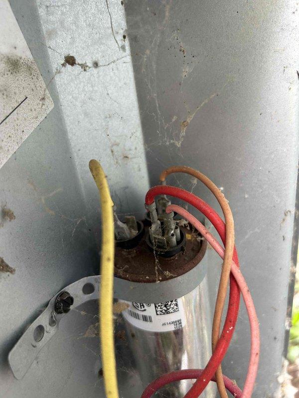 Responded to no cooling call on 10+ year old electric air conditioning system. Upon arrival, found indoor temperature at 82 degrees with thermostat set to 70 degrees and warm air blowing from registers. Outdoor Goodman condensing unit was not operating. Performed diagnostic evaluation of electrical components and identified failed dual run capacitor in outdoor unit. Capacitor showed visible signs of deterioration and tested out of specification. Replaced defective capacitor with new OEM equivalent component, restored power to system, and verified proper compressor and condenser fan motor operation. System cycled on successfully and began producing cold air. Confirmed adequate airflow at indoor unit in basement and proper refrigerant pressures. Left system operating normally with cooling restored.