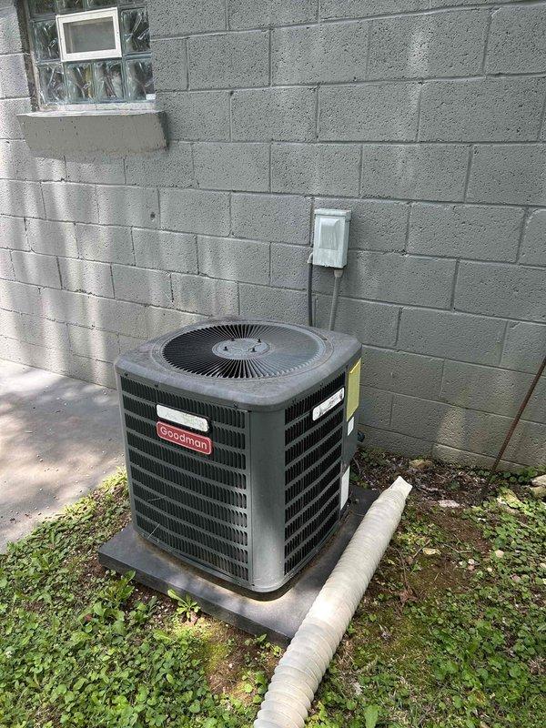 Responded to no cooling call on 10+ year old electric air conditioning system. Upon arrival, found indoor temperature at 82 degrees with thermostat set to 70 degrees and warm air blowing from registers. Outdoor Goodman condensing unit was not operating. Performed diagnostic evaluation of electrical components and identified failed dual run capacitor in outdoor unit. Capacitor showed visible signs of deterioration and tested out of specification. Replaced defective capacitor with new OEM equivalent component, restored power to system, and verified proper compressor and condenser fan motor operation. System cycled on successfully and began producing cold air. Confirmed adequate airflow at indoor unit in basement and proper refrigerant pressures. Left system operating normally with cooling restored.