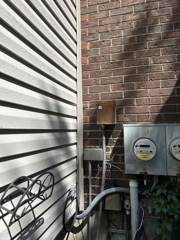 Responded to service call for inoperative heat pump system with no heating or cooling capability. Upon arrival, located outdoor Trane heat pump unit mounted on exterior brick wall near electrical meter assembly. Performed diagnostic evaluation of unit, which showed evidence of age and weathering with visible discoloration on cabinet surfaces. Inspected electrical connections, conduit runs, and power supply from nearby meter box. Assessed unit operation, checked refrigerant lines, and examined control wiring. Documented equipment condition through photographs showing permit stickers and manufacturer data plate for reference. Determined root cause of system failure and completed necessary repairs to restore heating and cooling operation to the heat pump system.