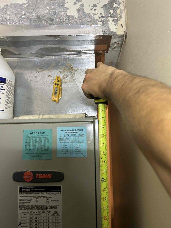 Responded to service call for inoperative heat pump system with no heating or cooling capability. Upon arrival, located outdoor Trane heat pump unit mounted on exterior brick wall near electrical meter assembly. Performed diagnostic evaluation of unit, which showed evidence of age and weathering with visible discoloration on cabinet surfaces. Inspected electrical connections, conduit runs, and power supply from nearby meter box. Assessed unit operation, checked refrigerant lines, and examined control wiring. Documented equipment condition through photographs showing permit stickers and manufacturer data plate for reference. Determined root cause of system failure and completed necessary repairs to restore heating and cooling operation to the heat pump system.