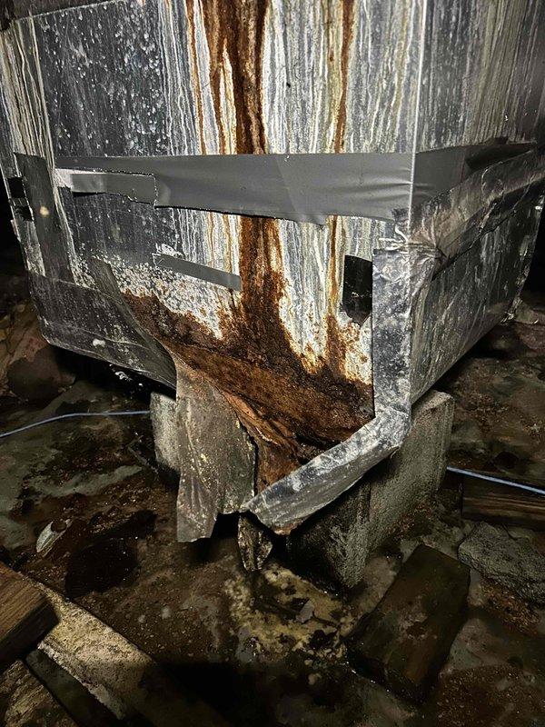 Responded to no cooling complaint for commercial HVAC system serving kitchen, front lobby area, laundry room, and medical office spaces. Upon inspection, discovered evaporator coil with severe rust corrosion and deterioration throughout, along with extensive moisture damage to metal ductwork and plenum assembly. Found multiple holes and weak points in duct sections with heavy rust streaking, mineral deposits indicating prolonged condensation issues, and previous failed tape repair attempts. Coil fins showed advanced degradation with rust buildup compromising heat transfer capability. System failure attributed to combination of age-related deterioration, chronic moisture exposure in installation environment, and high usage patterns from frequent door traffic during cooling season. Documented equipment condition with photos showing extent of corrosion damage to both evaporator coil and surrounding duct components. Recommended complete replacement of indoor air handler unit and associated