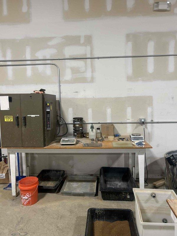 Conducted electrical estimate for warehouse facility requiring outlet installation and relocation. Assessed industrial workspace with high ceilings, concrete flooring, and multiple workstations containing manufacturing equipment and metal stock tanks. Evaluated existing electrical infrastructure including main electrical panel with conduit routing and determined optimal placement for new outlet locations to support ongoing operations. Documented current electrical configuration and workspace layout to develop comprehensive installation plan for relocating existing outlets and adding new receptacles throughout the facility.