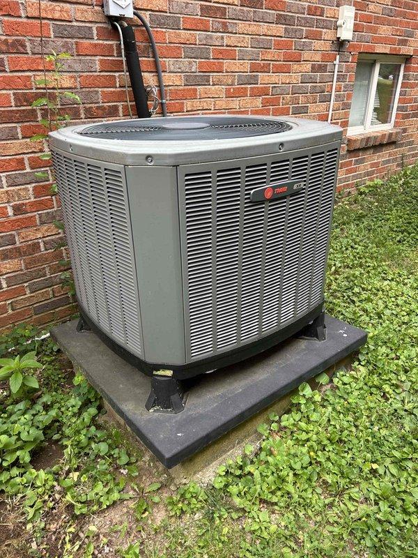 Responded to no cooling call on 9-year-old Trane heat pump system with outdoor condenser unit and basement-located air handler. Performed comprehensive diagnostic evaluation of both indoor and outdoor components to determine cause of system failure. Inspected electrical connections, refrigerant lines with service valves, condenser coil condition, and air handler operation. Unit showed no visible signs of physical damage or deterioration, with equipment appearing well-maintained on concrete pad with proper vibration isolation. Completed full system assessment and documented equipment condition with photographic records of outdoor condenser unit positioned against building foundation and indoor air handler installation in mechanical room.